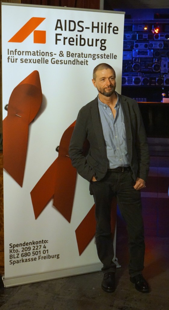 Ralf König vor dem AH-Plakat fotografiert